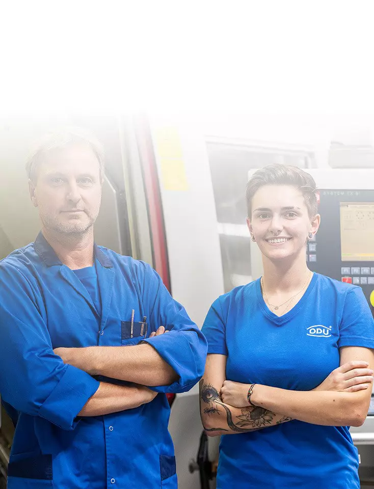 Two ODU employees stand next to each other in front of a machine.