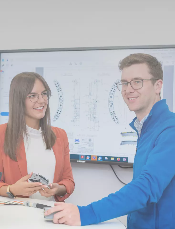 Two ODU employees are having a conversation in front of a large monitor.