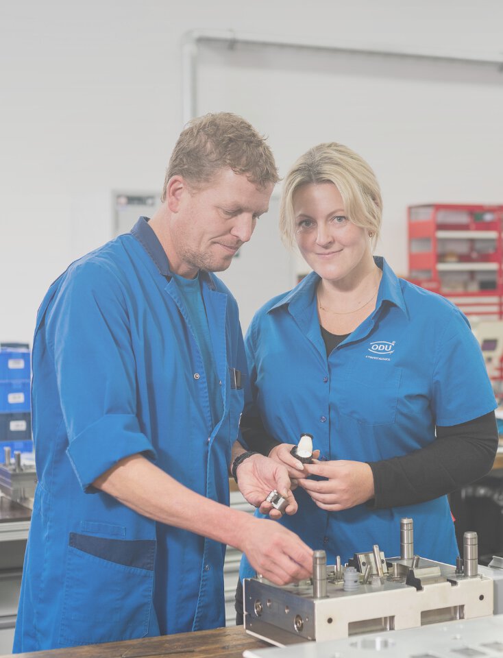 Two ODU employees have a technical discussion in front of a machine.