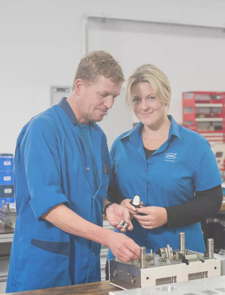 Two ODU employees have a technical discussion in front of a machine.