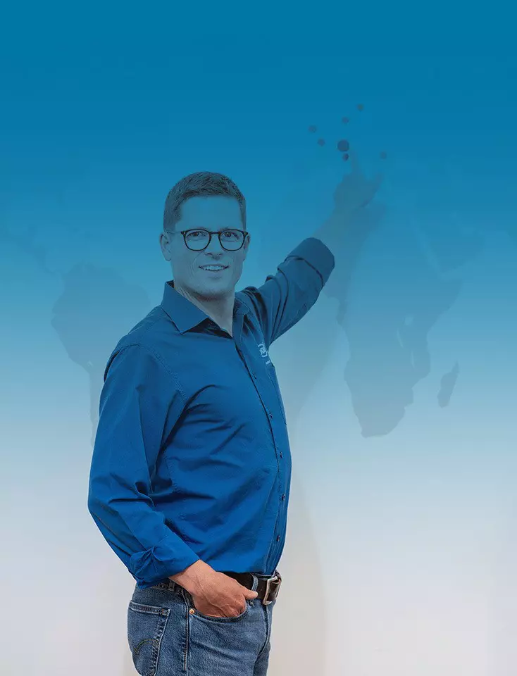 A man with glasses and a blue ODU shirt points to a world map.