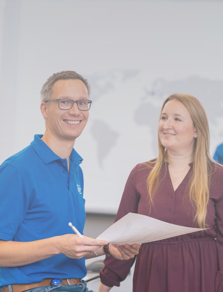 A woman is sitting at a desk and another woman is standing next to her.