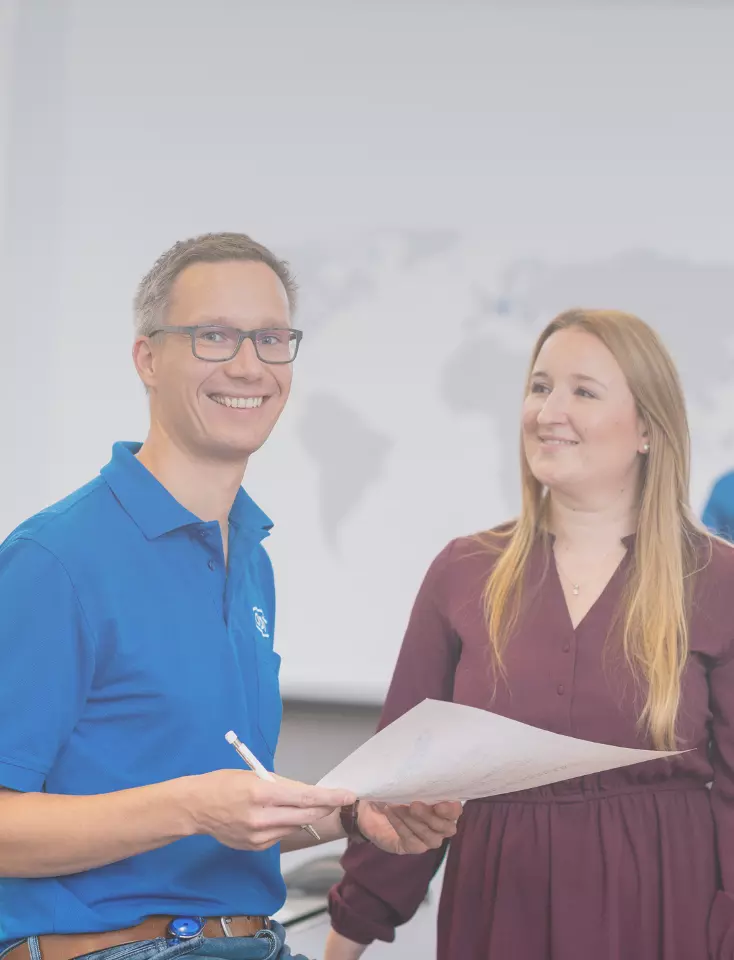 A woman is sitting at a desk and another woman is standing next to her.
