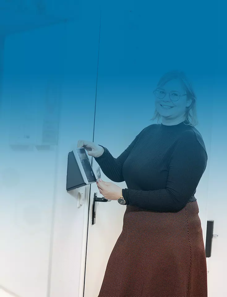 A woman lifts a card to the time recording device of a company.