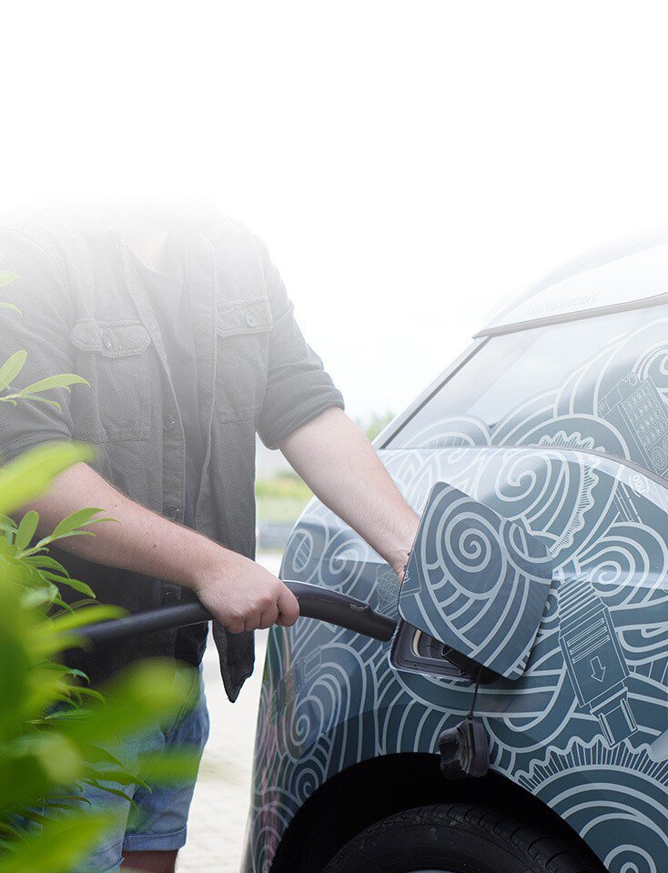 A man charges a car with an electric cable.