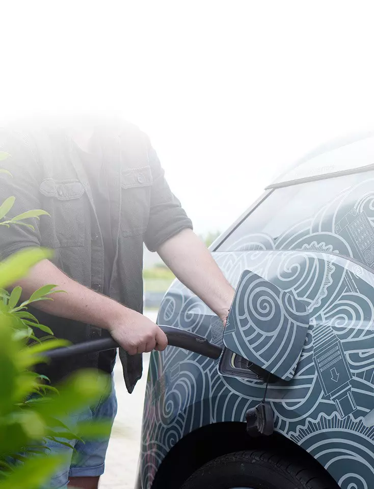 A man charges a car with an electric cable.