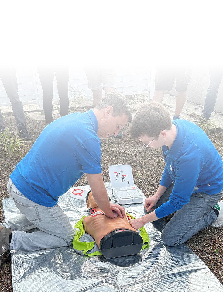 Two ODU employees kneel on the floor and practice chest compressions on a dummy.