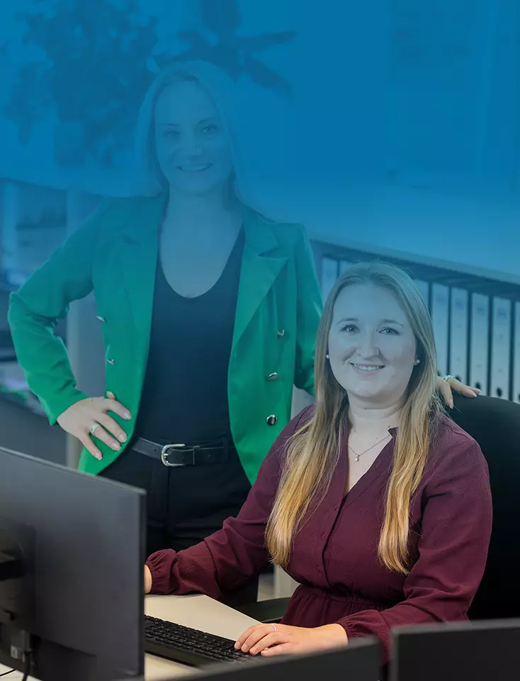 A woman is sitting at a desk and another woman is standing next to her.
