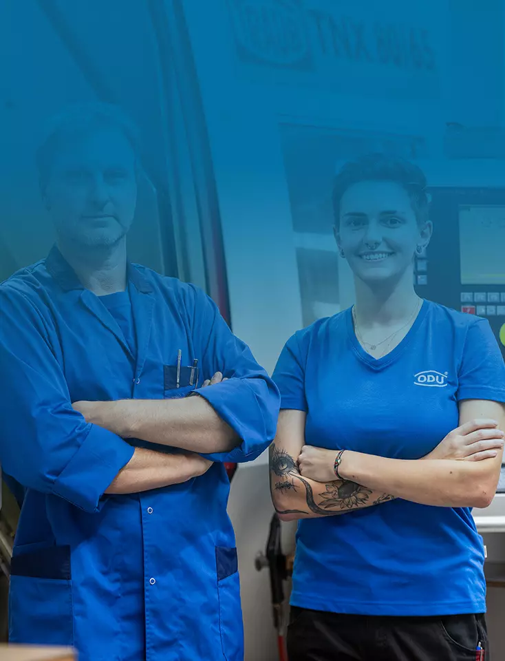 An ODU employee and an employee stand next to each other in front of a machine.